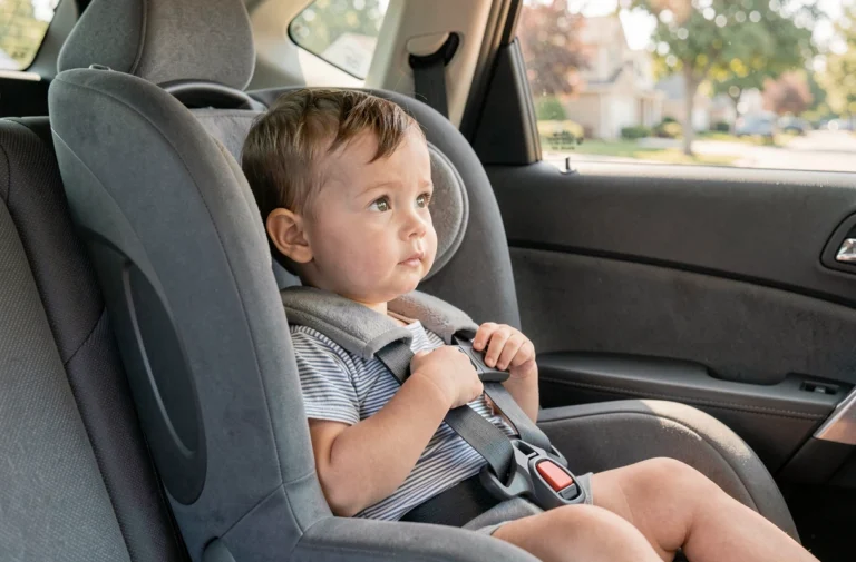 Tout-petit installé dans un siège auto dos à la route homologué, attaché avec un harnais réglable dans un SUV familial